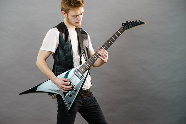 Tiener hardcore man dragen metalen outfit spelen op gitaar zware rockmuziek. - Foto, afbeelding