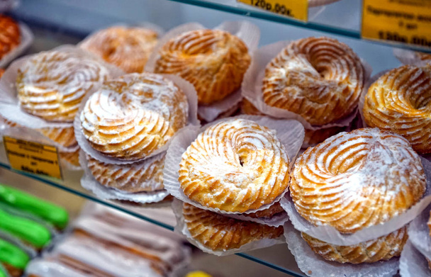 Rings with cottage cheese, sprinkled with powdered sugar, on the counter, in a pastry shop. - Photo, Image