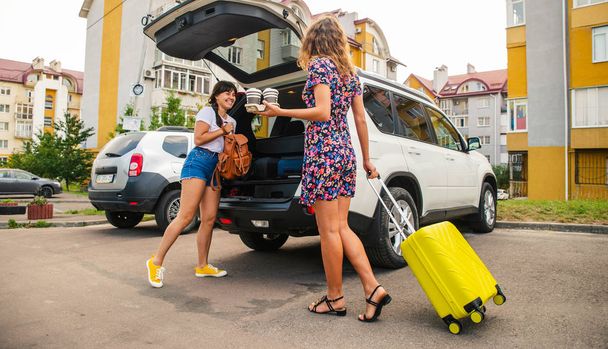 two woman packing luggage in car trunk. road trip - Photo, Image