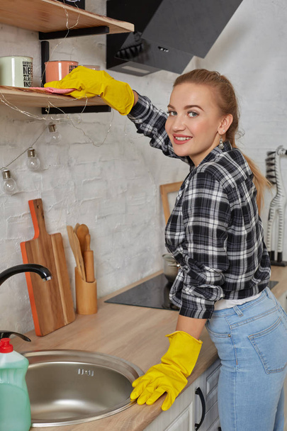 Femme en gants nettoyage de meubles avec chiffon à la maison cuisine
. - Photo, image
