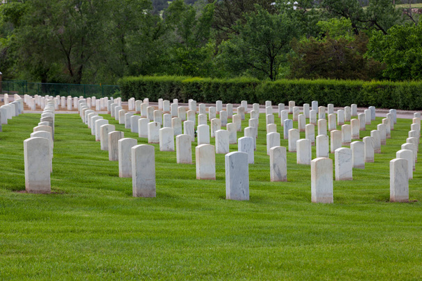 Надгробия из белого мрамора, обозначающие могилы американских солдат на склоне холма Национального кладбища Хот-Спрингс в Южной Дакоте
. - Фото, изображение