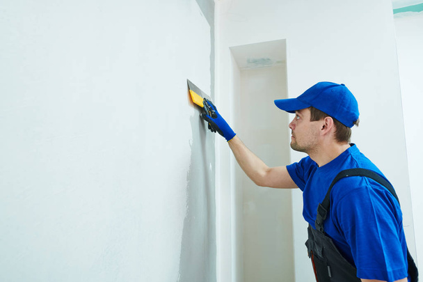 refurbishment. Plasterer worker spackling a wall with putty - 写真・画像