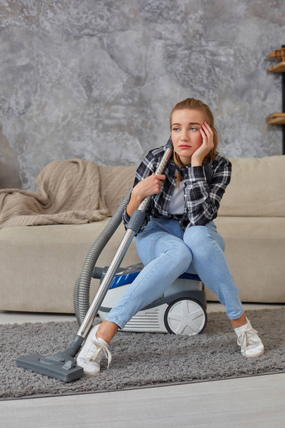 Young woman with cleaning equipment ready to clean house, sitting on couch. Fatigue - Photo, Image