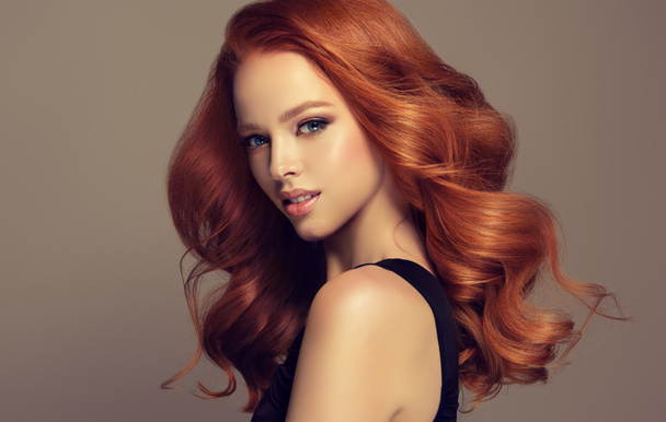 Fiatal, vörös hajú nő, terjedelmes haj. Gyönyörű modell, hosszú, sűrű, göndör frizura - Fotó, kép
