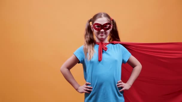 Młoda dziewczyna superbohatera z czerwony płaszcz i maska na oczy - Materiał filmowy, wideo