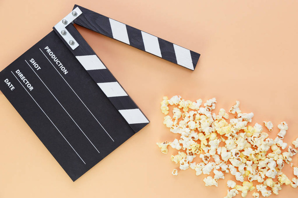 black clapperboard and popcorn with free space for text isolated on color background - Photo, Image