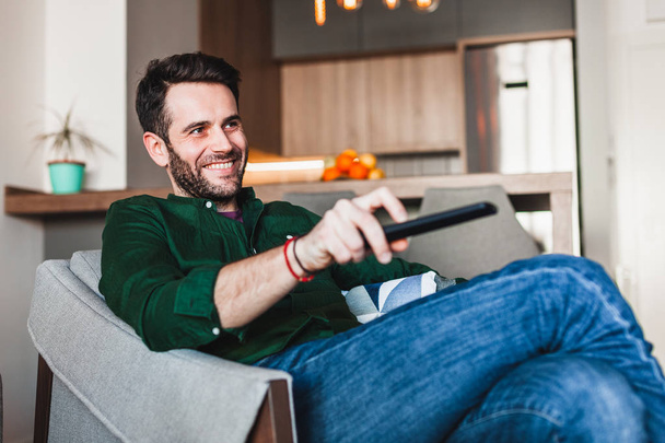 Young man holding remote controller watching tv  - Photo, Image