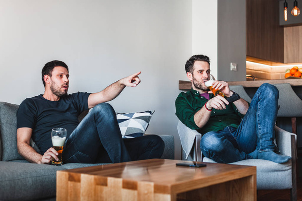 Two guys drinking beer watching sports on TV - Zdjęcie, obraz