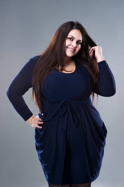 Happy plus size fashion model in blue dress, sexy fat woman on gray studio background - Photo, Image