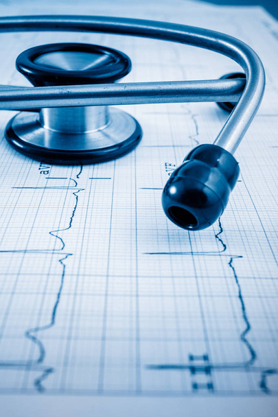 Estetoscopio en concepto de cardiograma para el cuidado del corazón en el escritorio.Imágenes tonificadas azules
. - Foto, imagen