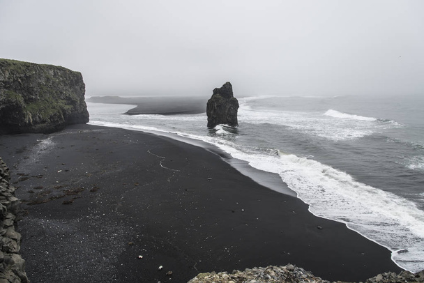 霧、曇りの日の断崖や奇岩を示すアイスランドの Kirkjufjara ビーチ - 写真・画像