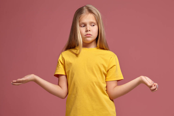 Uma menina de t-shirt amarela. não sabe a resposta
 - Foto, Imagem