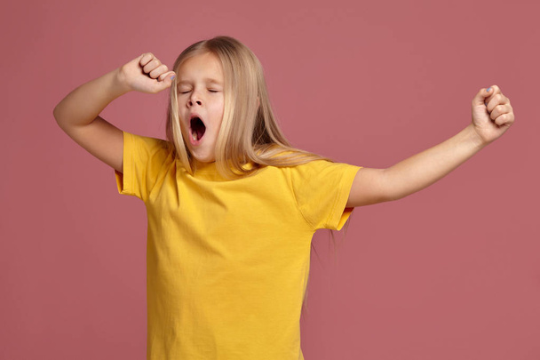 Sarı tişört, küçük kız. uzanıyor ve yawns - Fotoğraf, Görsel