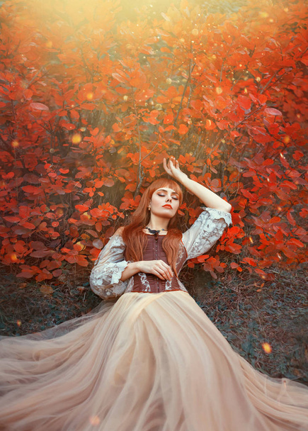 warm art photo of sleeping beauty, girl with fiery red hair lies on ground in dense forest under orange leaves in bright yellow sunlight, wonderful enchanted princess, new story about Snow White - Foto, Imagem