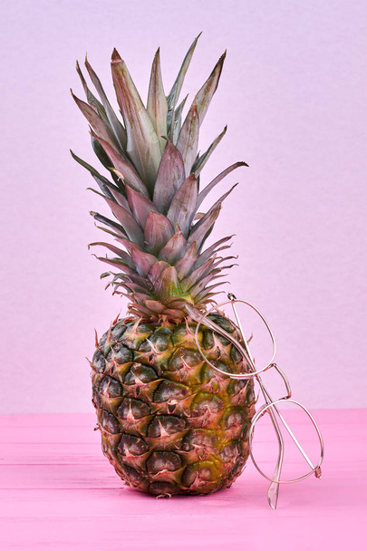 Whole pineapple and eyeglasses on color background. - Фото, зображення