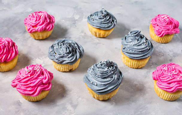 Tasty pink and grey cupcakes in a row on concrete background - Fotó, kép