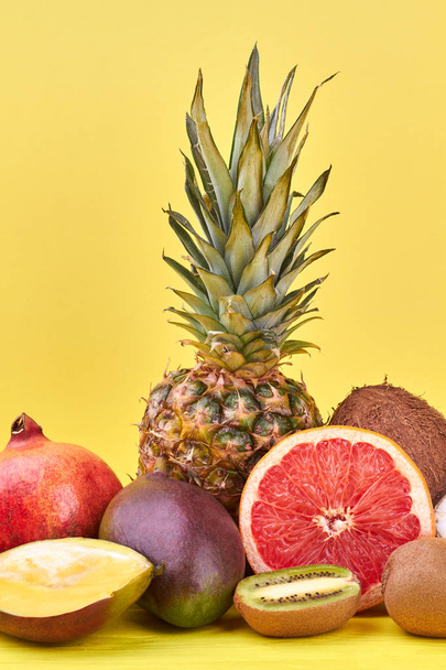 Летняя композиция из экзотических фруктов. Вкусные тропические фрукты, включая ананас, гранат, манго, кокос, грейпфрут и фрукты киви на цветном фоне
. - Фото, изображение