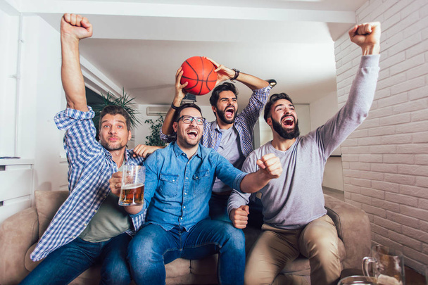 Happy přátelé nebo basketbalové fanoušci sledují basketbalový zápas v televizi a slaví vítězství doma. Koncepce přátelství, sportu a zábavy. - Fotografie, Obrázek