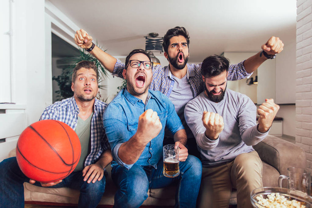 Amici felici o appassionati di basket guardando la partita di basket in tv e celebrando la vittoria a casa.Amicizia, sport e divertimento concetto
. - Foto, immagini