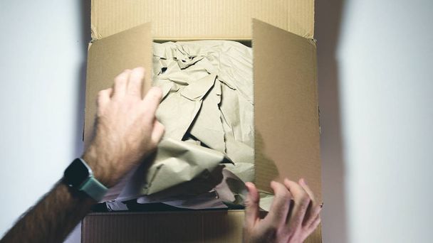 Man unpacking unboxing cardboard delivered parcel - Fotografie, Obrázek