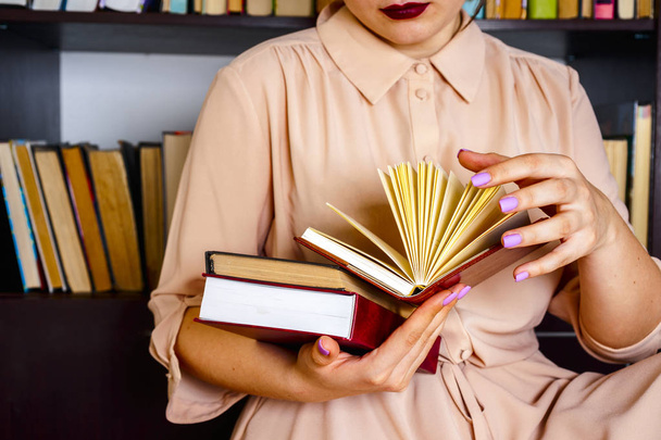 Una joven con un vestido ligero está leyendo un libro. Las manos femeninas sostienen un libro en sus manos
 - Foto, Imagen