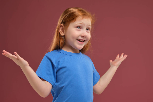 Portrait of cute redhead emotional little girl on red background - Foto, imagen