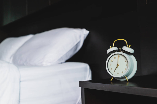寝室の木製ベッドサイド テーブルにレトロな灰色の目覚まし時計 - 写真・画像