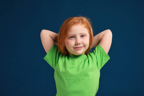 close up photo of little redhead emotional girl posing before camera on blue background - Foto, Imagen