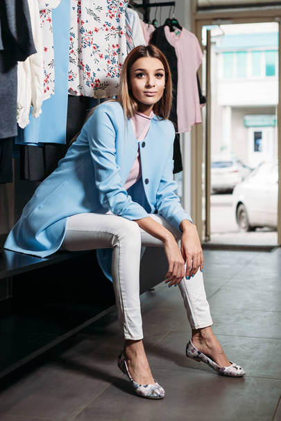 Beautiful model brunette girl in stylish clothes, posing in clothing store, a new trend of clothes. Banner for a clothing store. For showrooms and fashion stores, cover stories, interior studio - Photo, Image