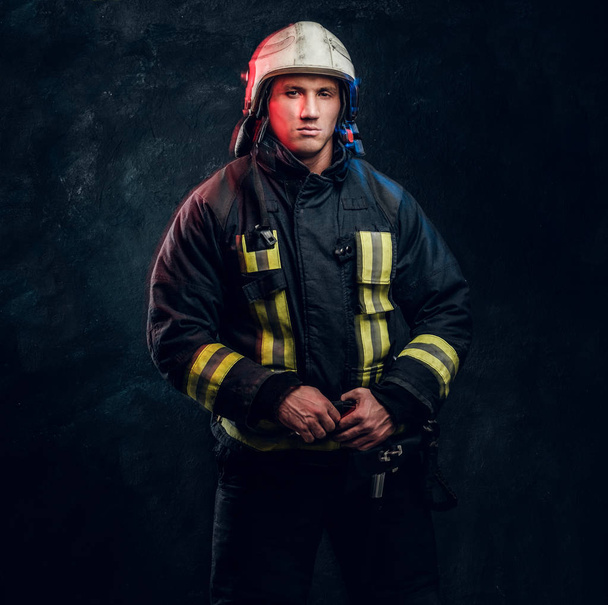 Portrét hasič oblečený v uniformě a ochrannou přílbu, pohled z boku s jistý pohled - Fotografie, Obrázek