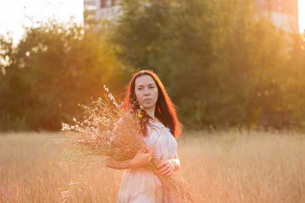 Menina bonita em um vestido de luz recolhe flores selvagens
 - Foto, Imagem