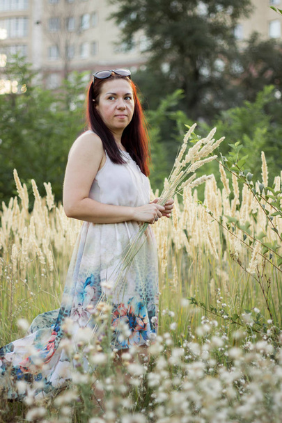 Hermosa chica en un vestido ligero recoge flores silvestres
 - Foto, Imagen