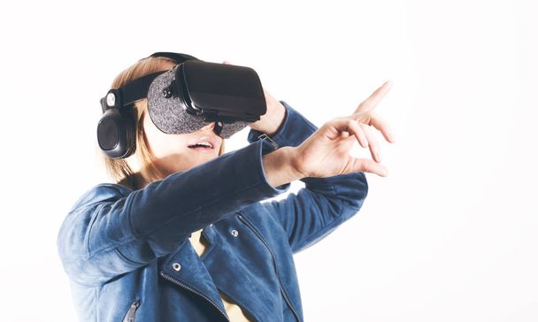 A young woman is wearing virtual reality glasses and reaching for something with his hands - Foto, Bild