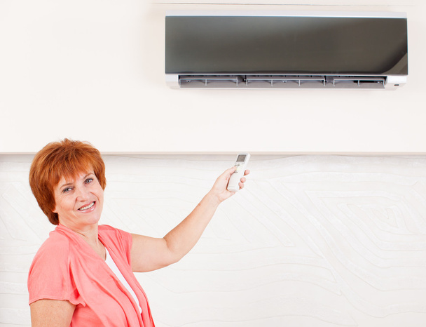Woman holding a remote control air conditioner - Foto, afbeelding