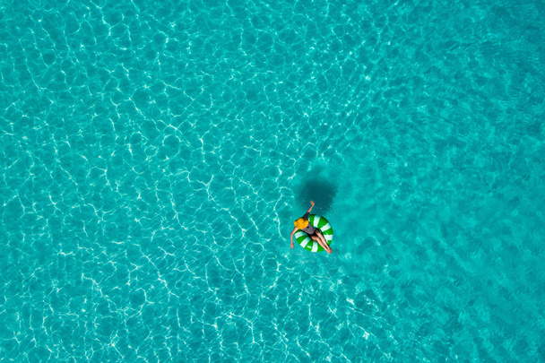 Пташиного польоту slim жінка плавання на пончик кільце плавати в прозорих бірюзове море у країні Сейшельські острови. Літній морський пейзаж з дівчиною, гарний хвилі, барвисті води. Вид зверху від drone - Фото, зображення