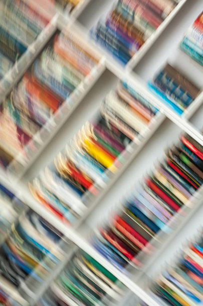 Wazig beeld van kleurrijke boekenplank in gedaan aan het bewegen van de camera. - Foto, afbeelding