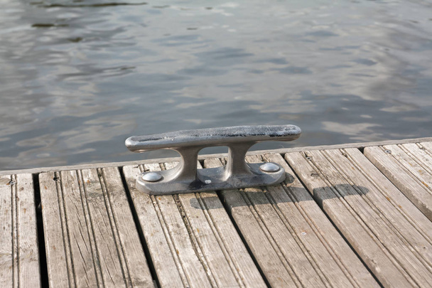 Mooring hook on wooden pier on the river in Finland at summer sunny day. - Photo, Image