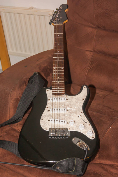 Vecchia chitarra elettrica bianca nera sulla poltrona
. - Foto, immagini