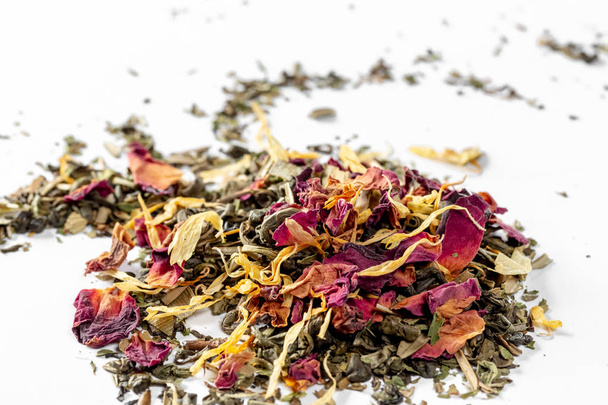 Green tea with dried flower petals and pieces of citrus on white background. Dried tea for welding. Diet and healthy drink - Foto, imagen