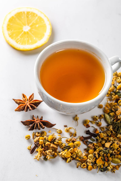 A Cup of green tea with dried chamomile flowers and a slice of cut lemon on a white background. Diet and healthy drink. Flatley. Top view - Zdjęcie, obraz