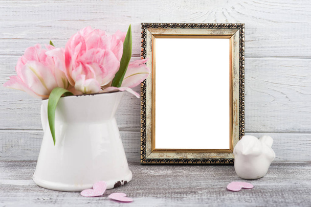 Flores de tulipán rosadas frescas en jarra, marco de fotos vacío sobre fondo rústico de madera
 - Foto, imagen