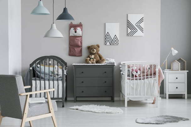 Pink organizer on wall of trendy baby bedroom with two cribs and chest of drawers - Photo, Image