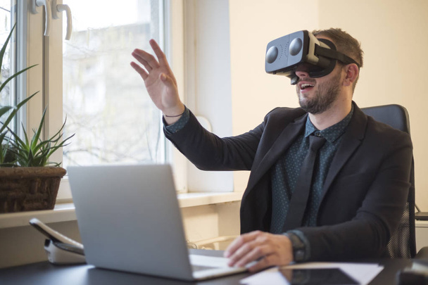 бізнесмен закінчує свою роботу і приймає окуляри віртуальної реальності за віконним чорним столом з ноутбуковими паперами телефону VR
 - Фото, зображення