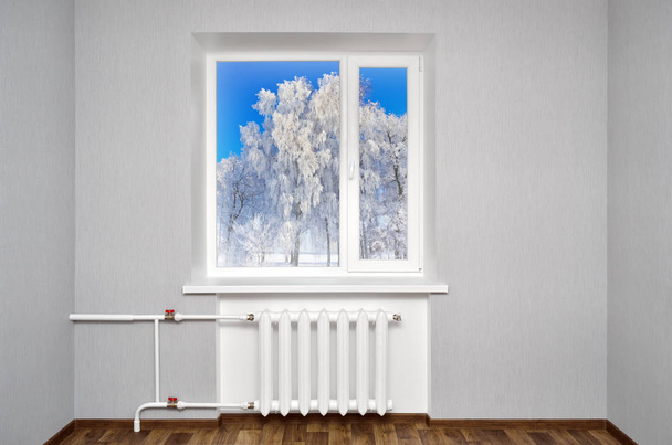 Wit venster in lege ruimte met verwarming en grijze muren. Prachtig uitzicht vanuit het raam van het huis. - Foto, afbeelding