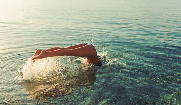 mujer saltar en el agua al atardecer. deportista nadando en el mar o en el agua del océano. vacaciones de verano y viajes. actividad en la playa y energía. chica buceo en la puesta del sol
 - Foto, imagen