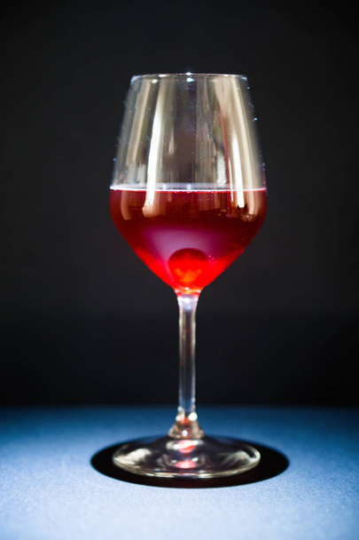 Un bicchiere di vino rosso, lo sfondo è nero, il serbatoio è illuminato con una luce direzionale dall'alto, l'ombra è sdraiata direttamente sotto il vetro, come se un supporto per il serbatoio
 - Foto, immagini