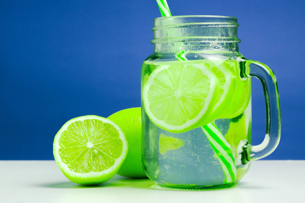 Odświeżanie zielonych owoców cytrusowych lemoniady w słoiku. letni koktajl z cytryny dojrzałe i soczyste i na stół biały. witaminy - Zdjęcie, obraz