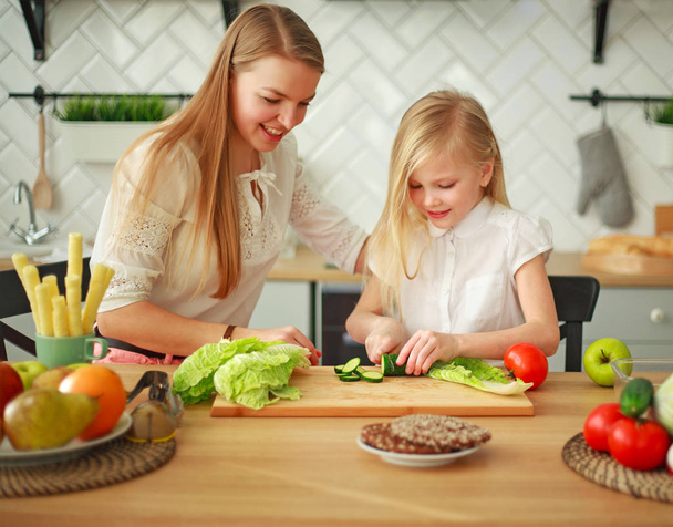 Madre con su hija en la cocina preparando alimentos saludables con verduras frescas, estilo de vida de crianza en el hogar
 - Foto, imagen