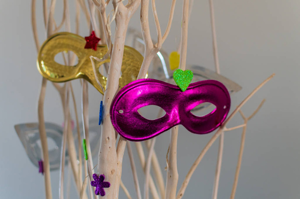 Máscaras de carnaval de colores colgando de ramas para la decoración
 - Foto, Imagen