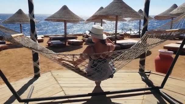 Женщина охлаждается в гамаке на пляже, отдых на море, отдых на пляже, море и отдых, песок и голубая вода
 - Кадры, видео